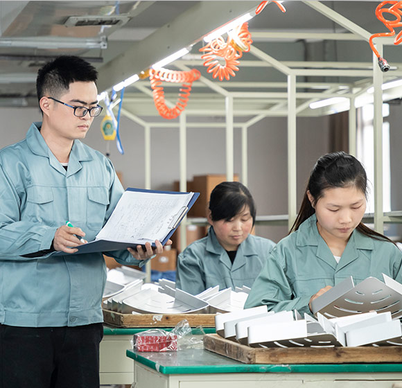 A quality inspector is inspecting workers who assemble and pack shower racks